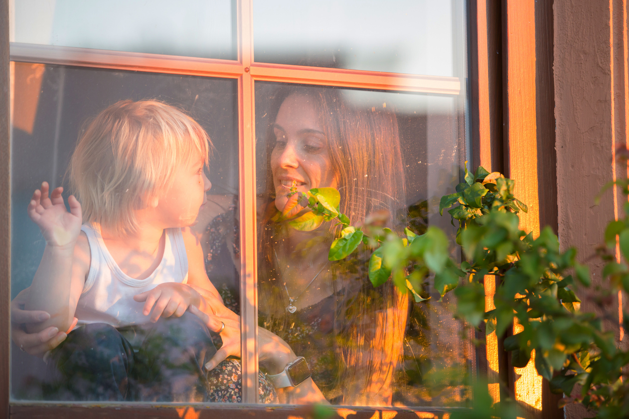 Woman with her toddler looking out a sunny window