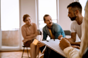 Counselor drafting a specialty program plan for patients nearby