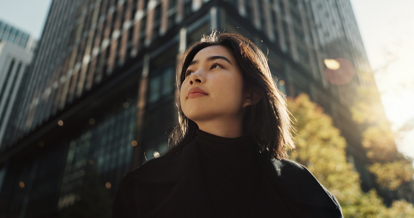 Woman walking in a city, looking hopefully upward