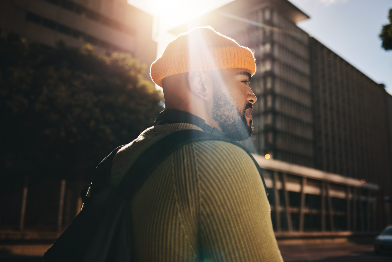 Man walking in a city, backlit by the sun