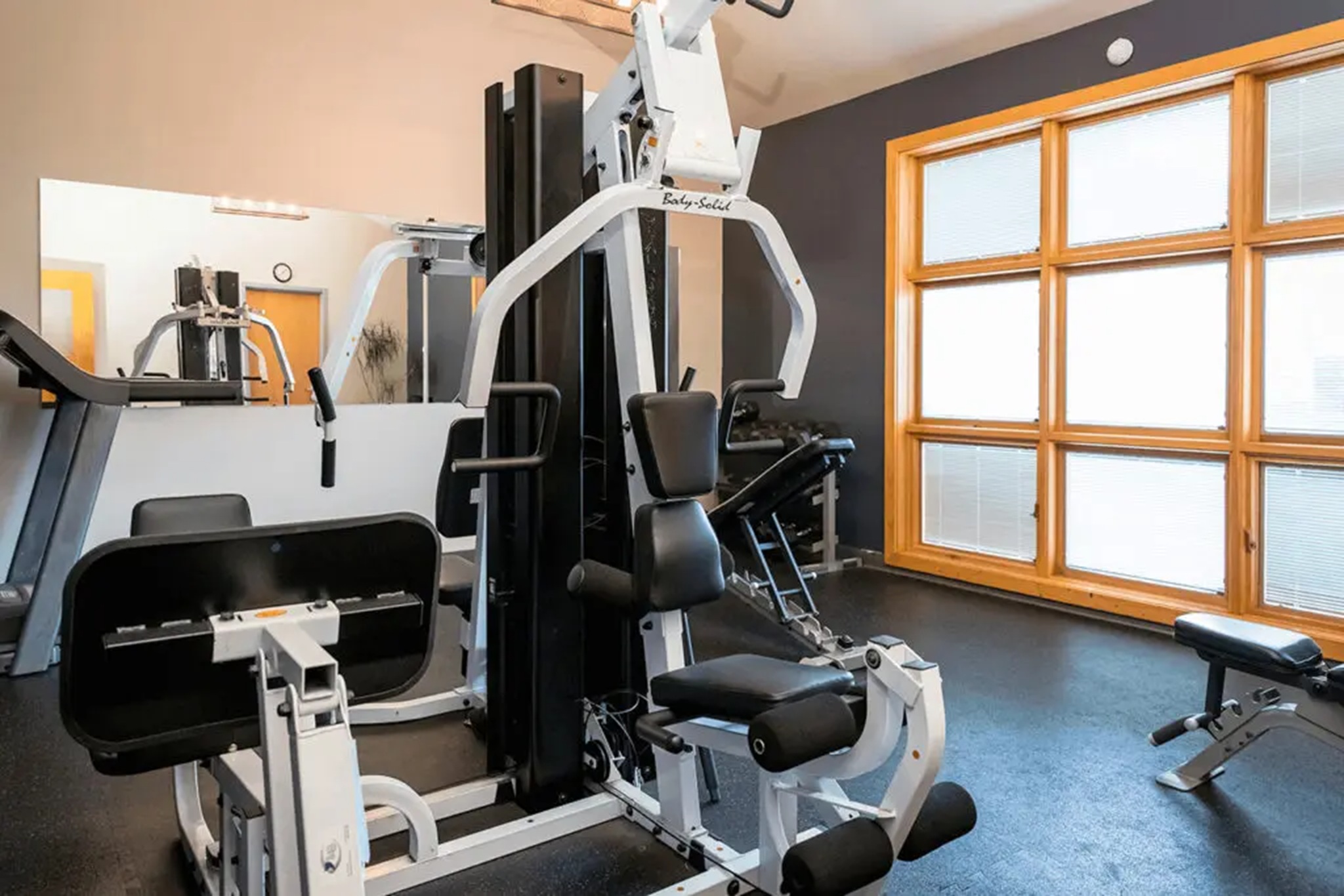 Fitness room with bright windows, camera focusing on a weight machine