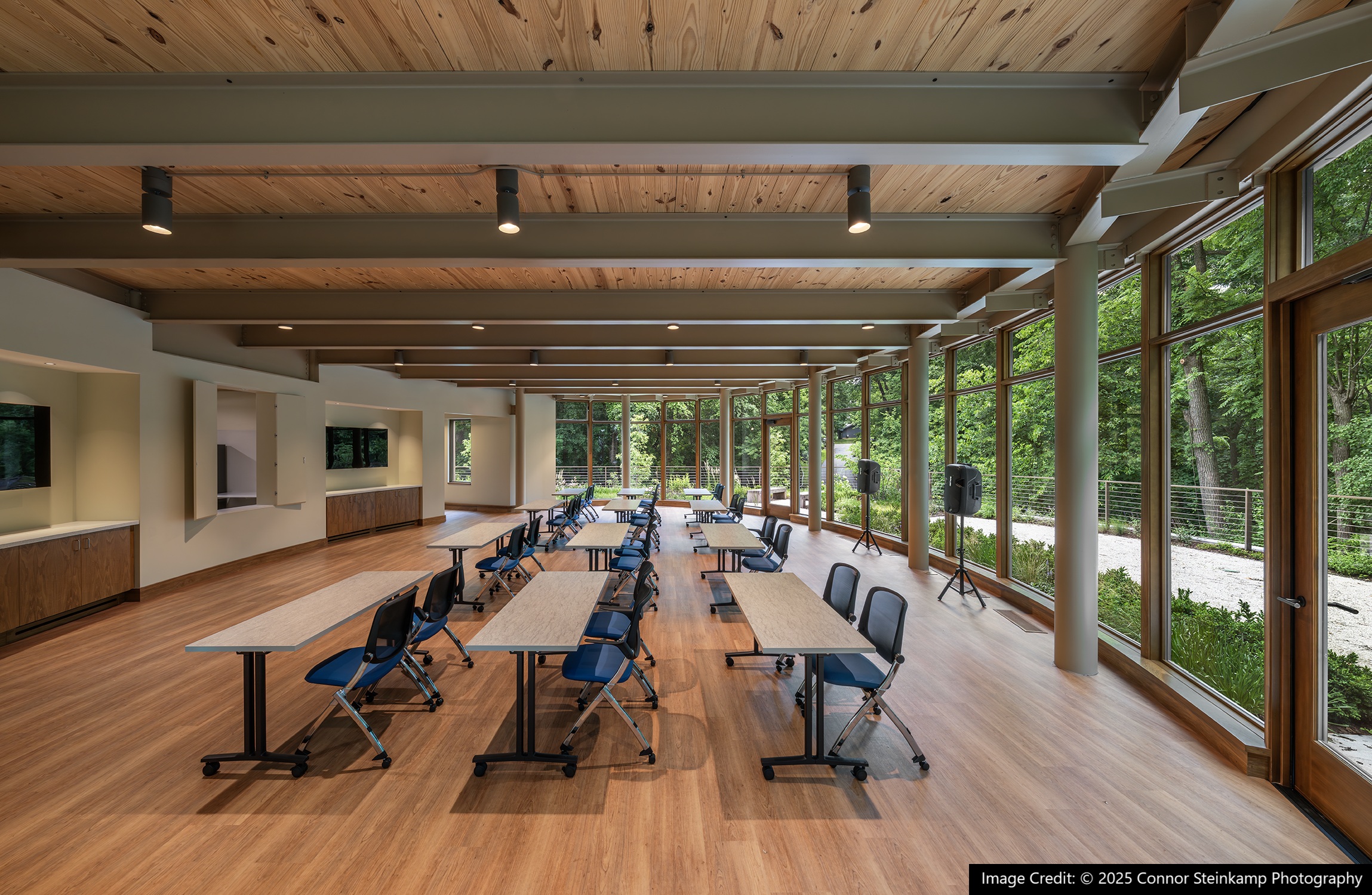 Open room with wooden floors and floor to ceiling windows.
