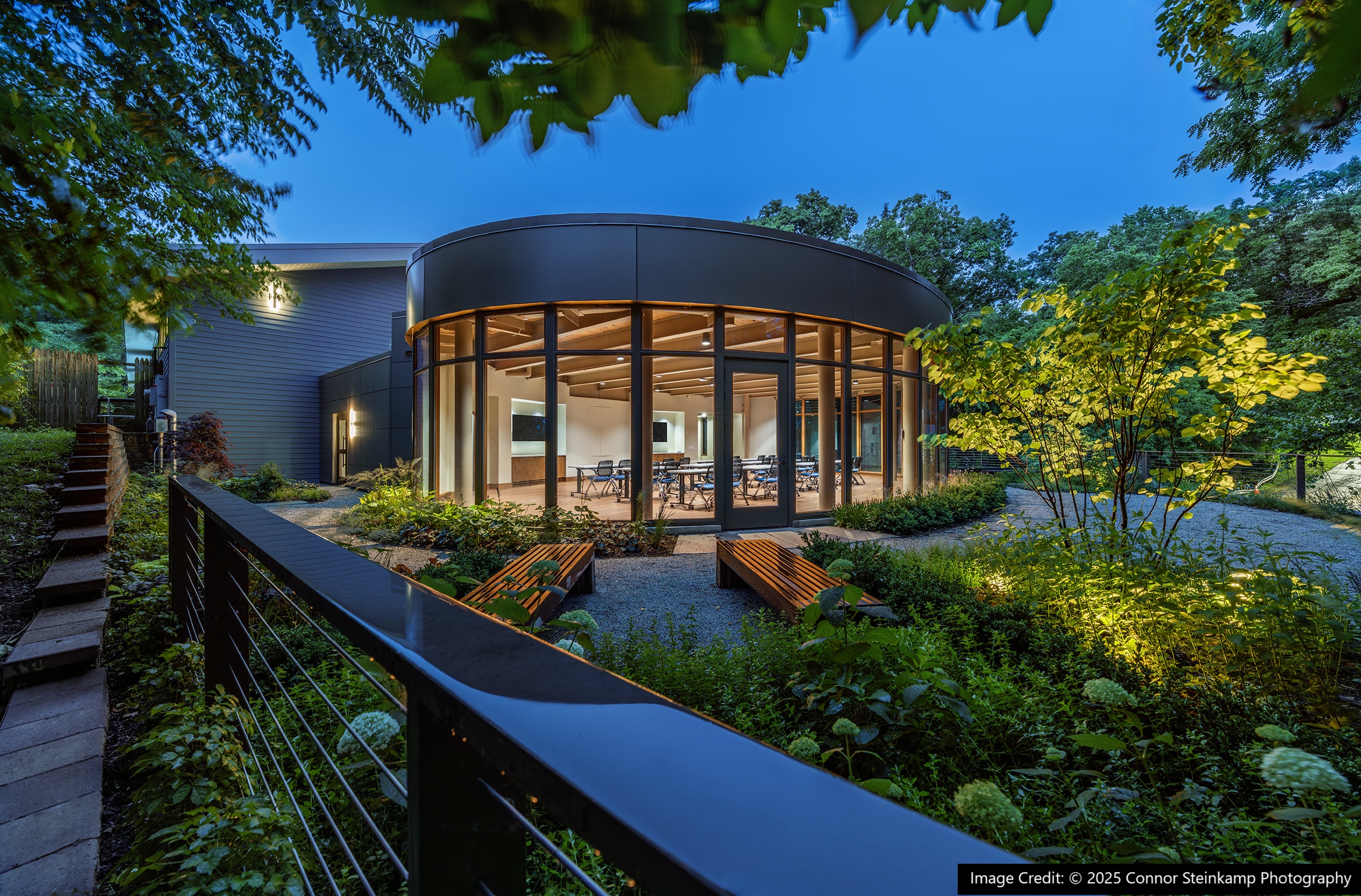 Garden space at night outside a building with floor to ceiling windows